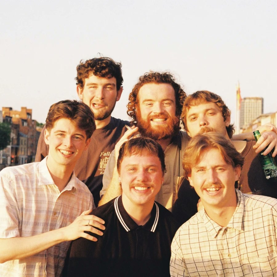 The band grinning together on a sunny rooftop